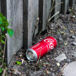 Coca-Cola-burk liggandes vid ett plank vid en stengata